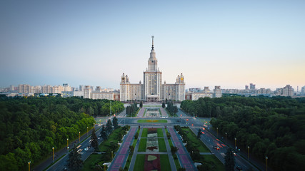 Wall Mural - Motion of Moscow State University in the evening, aerial view. Camera moving towards MSU, showing also its alleys and outdoor lighting gradually turning on.