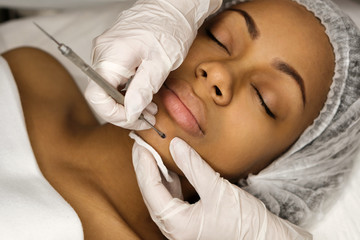 Procedure mechanical face cleaning in beauty salon. Afro american young model getting cosmetic face skin care and treatments in cosmetologist. Spa, cosmetology and wellness relaxation concept.