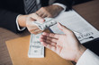 © wutzkoh - Entrepreneurs are receiving money that is a bribe of their partners with both of whom are corrupt in the company room.