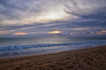 Phuket beach sunset, colorful cloudy twilight sky reflecting on the sand gazing at the Indian Ocean, Thailand, Asia.