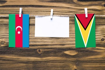 Wall Mural - Hanging flags of Azerbaijan and Guyana attached to rope with clothes pins with copy space on white note paper on wooden background.Diplomatic relations between countries.