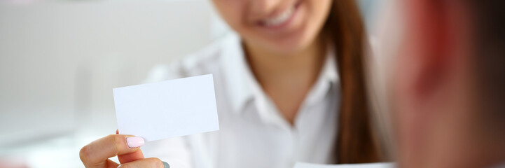 Female arm in suit give blank calling card to visitor