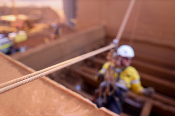 Wall Mural - Defocused rope access abseiler wearing safety full protection helmet harness working at height on tension line anchor point connecting with pulley descending construction site Perth, WA