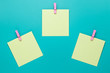 canvas print picture - Sticky note with pink pin on turquoise background. Yellow stickers on a green background, top view. Blank notes on notice board. Blank stickers on clothespins. Concept of planning. Copy space. 