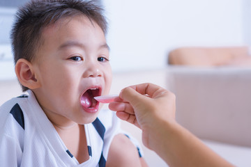 Asian children boy sick he take medicine by spoon