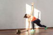 © khosrork - Lunge with spinal twist. Positive fit woman with bun hairstyle and in tight sportswear practicing while watching training video on tablet. indoor studio shot illuminated by sunlight from window