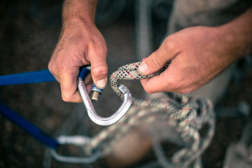 Wall Mural - Top view picture of industrial rope access worker hand connecting locking screwgate Karabiner 2.5 tone Nylon low stretch rope which its attached onto safety tape sling and beam structure anchor point