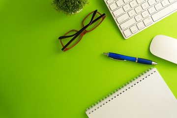 top view of blank paper page on green background office desk and different objects. minimal flat lay
