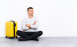 © luismolinero - Young handsome man sitting on the floor with a suitcase thinking an idea