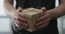 Young Man Shows Brown Craft Paper Gift Box