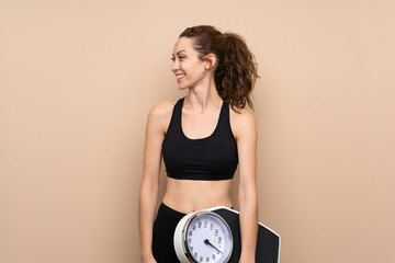 Young sport woman over isolated background with weighing machine