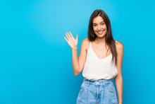 Young Woman Over Isolated Blue Background Saluting With Hand With Happy Expression