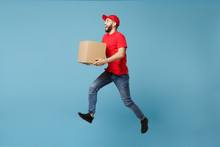 Delivery Man In Red Uniform Isolated On Blue Background, Studio Portrait. Male Employee In Cap T-shirt Print Working As Courier Dealer Hold Empty Cardboard Box. Service Concept. Mock Up Copy Space.