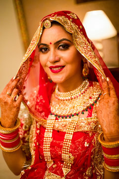 Portrait of beautiful happy indian woman wearing gold jewellery and traditional bridal outfit. 