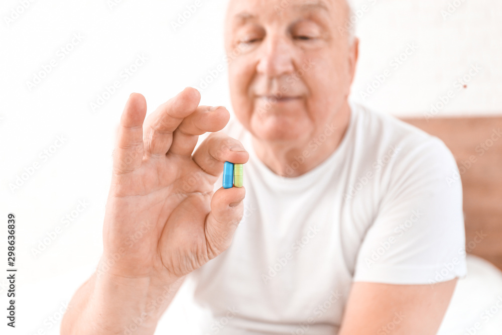 Elderly man with pills at home