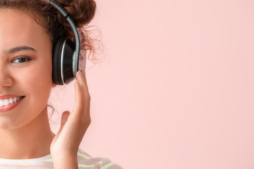 Wall Mural - Beautiful African-American woman listening to music on color background