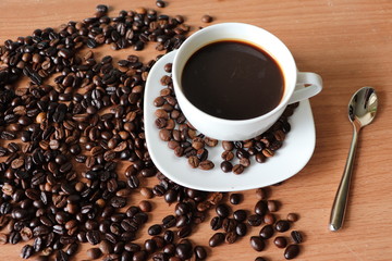 cup of coffee with beans on wooden table