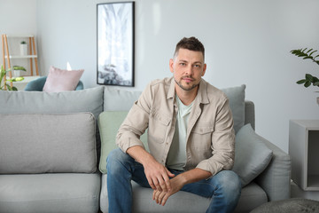 Wall Mural - Portrait of handsome man sitting on sofa at home