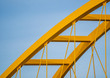 Yellow steel arch of a bridge against a steel blue sky