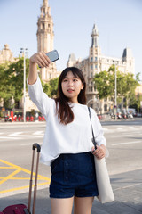 pretty chinese female tourist making selfie on the background of landmark