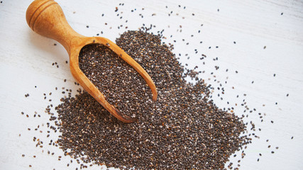 Nutritious chia seeds on a white background. chia seeds in bowl and a spoon on kitchen table top view. Healthy and diet superfood product.