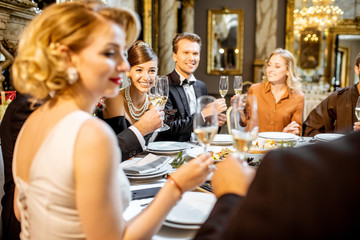 Elegantly dressed people having a festive dinner indoors