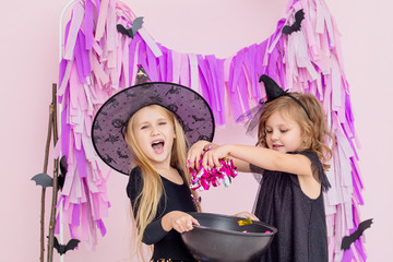 Two little beautiful cute children girls in carnival witch costumes in fashionable Halloween decorations