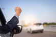 image of businessman in a celebrating success with a fist pump while driving in a car 