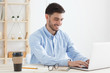 © Damir Khabirov - European guy typing on laptop in his office, wearing formal shirt