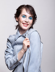 Wall Mural - Portrait of smiling female in blue jacket. Woman with unusual beauty makeup and wet hair, and blue shadows make-up.