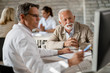 © Drazen - Happy senior man and his doctor using computer during consultations at clinic.