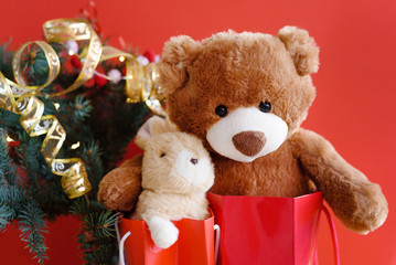 Christmas card with Teddy and banny in red gift bags under the Christmas tree.  With  holiday decoration and presents