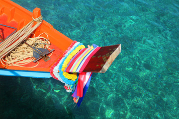 bow of a orange and blue colourful fishing boat with flower decorations, phuket, thailand.
