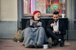 © alfa27 - Stylish office worker and beggar male sit eating on street and speaking. Man un tuxedo, poor male in old clothes