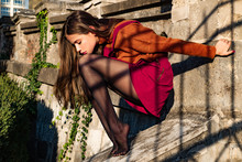 Sensual Tender Brunette Woman In Autumn Stylish Outfit. Girl Wearing Black Tights, Orange Sweater And Magenta Skirt Combination. Beautiful Young Natural Looking Girl.