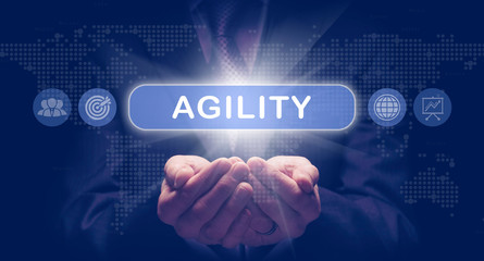 businessmans cupped hands holding a agility business concept on a computerised display.
