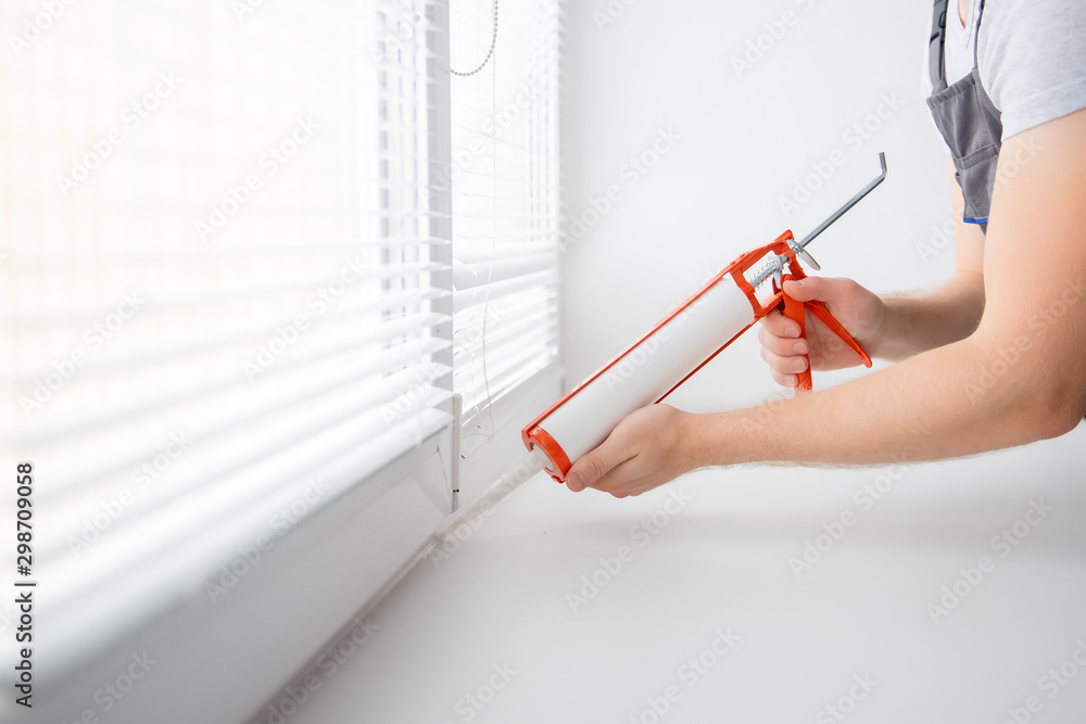 Construction worker use gun silicone tube for repairing and installing window in house - obrazy, fototapety, plakaty 