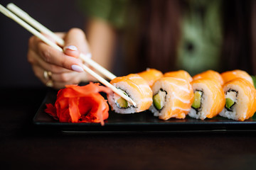 Hands eat sushi with chopsticks in cafe