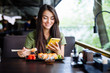 © F8  \ Suport Ukraine - Young woman texting on the phone while eating sushi in a restaurant