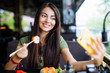 © F8  \ Suport Ukraine - Young woman is taking a selfie photograph while eating sushi in cafe