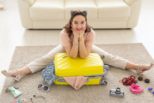 Holidays, Voyage And Travel Concept - Young Woman Packs A Suitcase At Home In The Bedroom, A Lot Of Things, Vacation And Yellow Suitcase