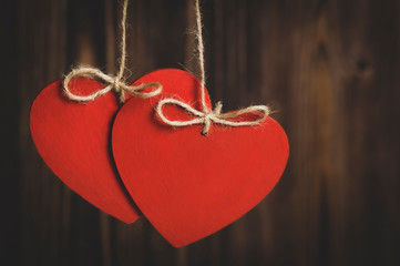 two hearts on ropes with bows on a wooden background, vignetting and toning the image