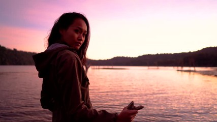 Wall Mural - young asian woman enjoying sunrise near lake in nature