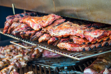 Grilled meat. Close-up cooking of large juicy pieces of raw, fat, natural, marinated pork meat, beef calves, rams on a griddle grill. A large round grill on the coals in which grilled meat