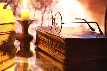 Wall Mural - Vintage glasses on an old retro book on a background of the moon. Reading a book by candlelight. The concept of book thrillers and novels.