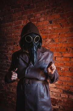 Terrible plague doctor on red brick background. Masked maniac with scalpel and scissors. Halloween and horror