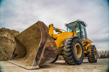 Wall Mural - Side view of a yellow bulldozer with dirty metal bucket and black rubber wheels