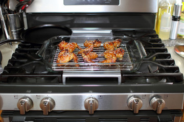 Wall Mural - Baked teriayki chicken wings from the oven resting on the stove top in a home kitchen.