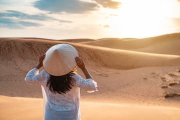 Young woman traveler looking sunset at red sand dunes in Vietnam, Travel lifestyle concept