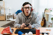 Nerd geek young adult man playing on video console enjoy online game. asian male gamer concentrated having competition on computer using joystick in messy bedroom at home. junk food trash indoors.
